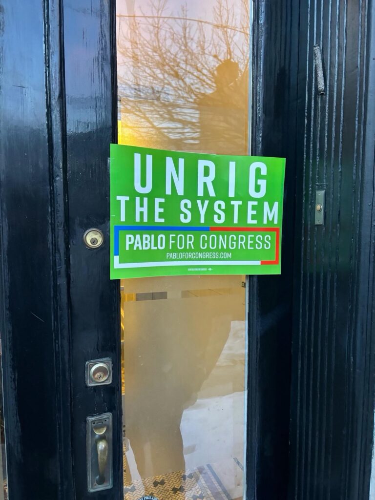 Desmantelar el sistema'. Un letrero de la campaña de Pablo Iván para el Congreso se ve en la ventana de un negocio local en el sur de Filadelfia, señalando su enfoque en la reforma y el cambio